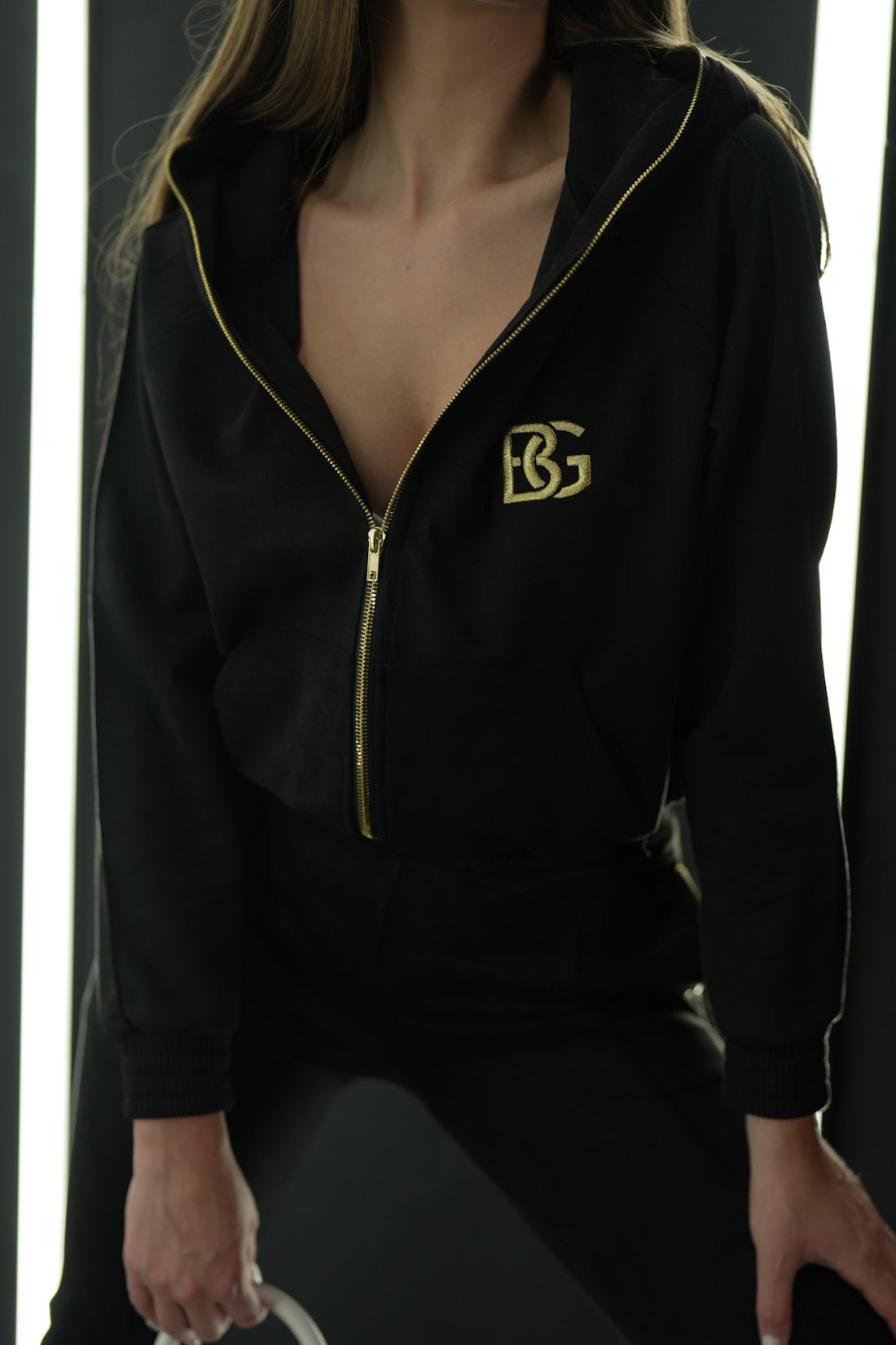 Detail zlatého loga BG Couture na čiernej súprave – model New Essentials.